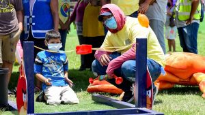 A fun outdoor festival game with children and adults playing in a park setting.