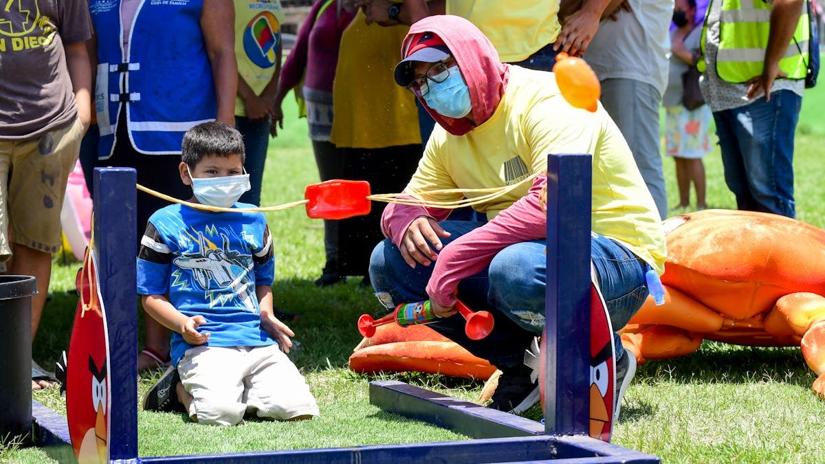 A fun outdoor festival game with children and adults playing in a park setting.