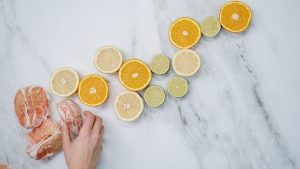 Overhead view of assorted citrus slices and a hand on a marble surface. Fresh and vibrant composition.